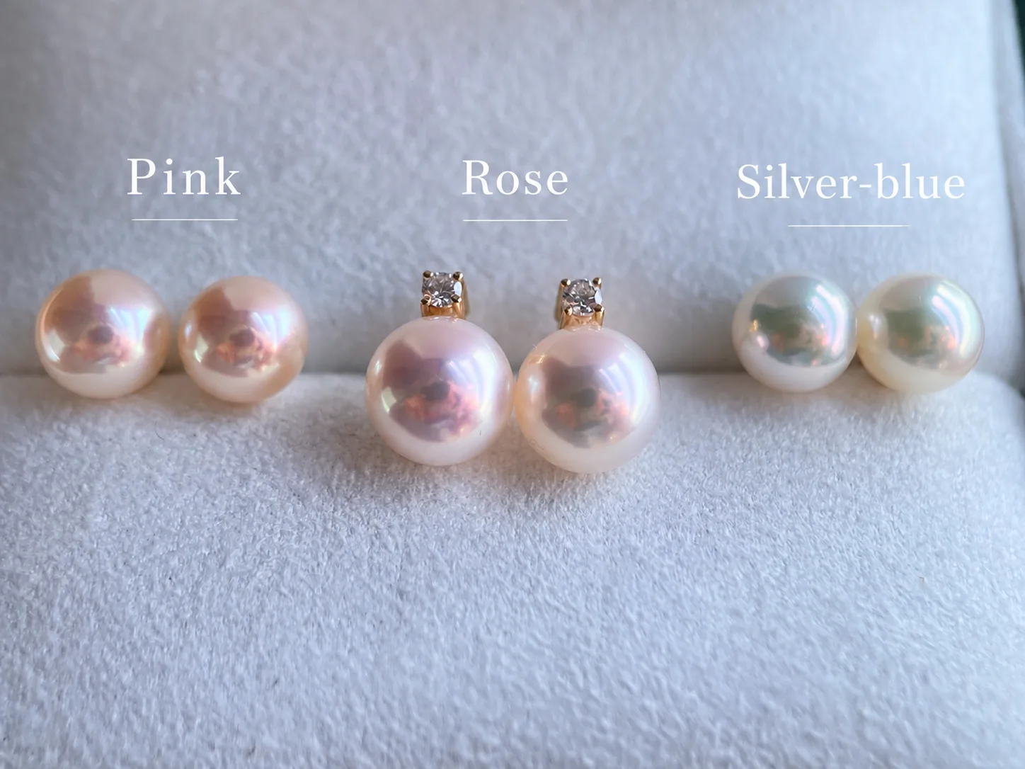 Akoya pearl studs labeled pink, rose, and silver-blue under the same lighting