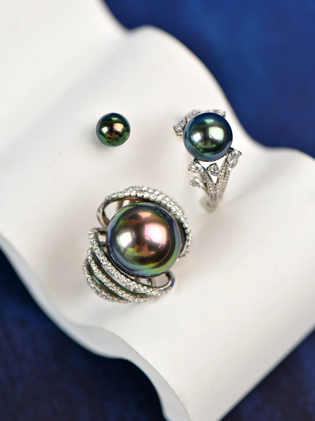 A dark iridescent pearl ring displayed with matching pearl studs