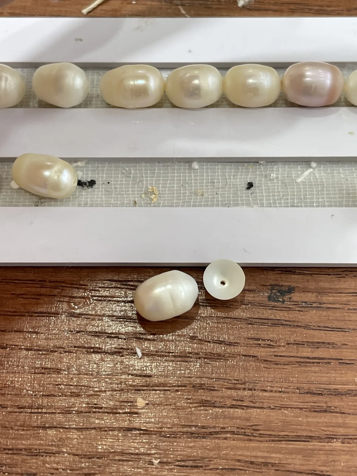 Baroque pearl beside a separated nacre cap with a drill hole