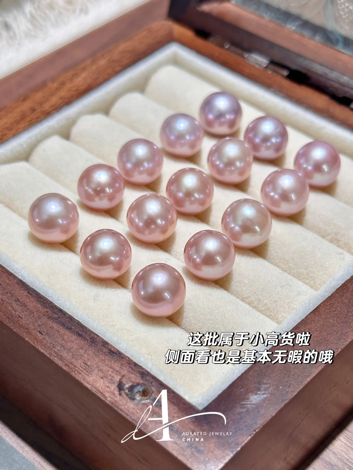Pink and lavender loose pearls arranged in a wooden jewelry box