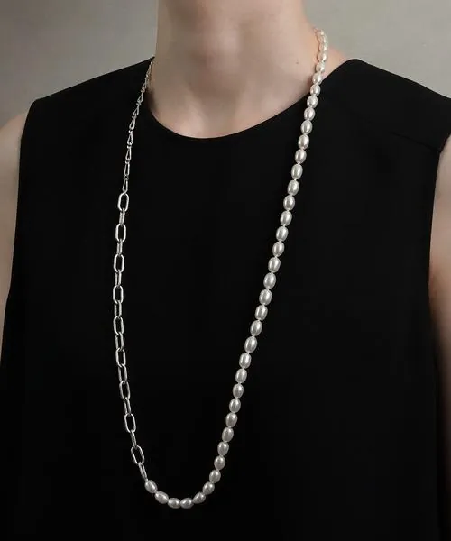 Long white pearl strand layered with a silver paperclip chain over a black sleeveless top