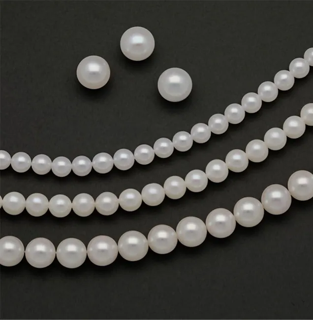 White pearl strands and loose round pearls on a dark background