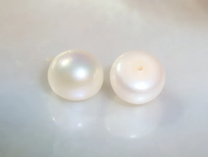 Two white button-shaped pearls showing their domed profiles