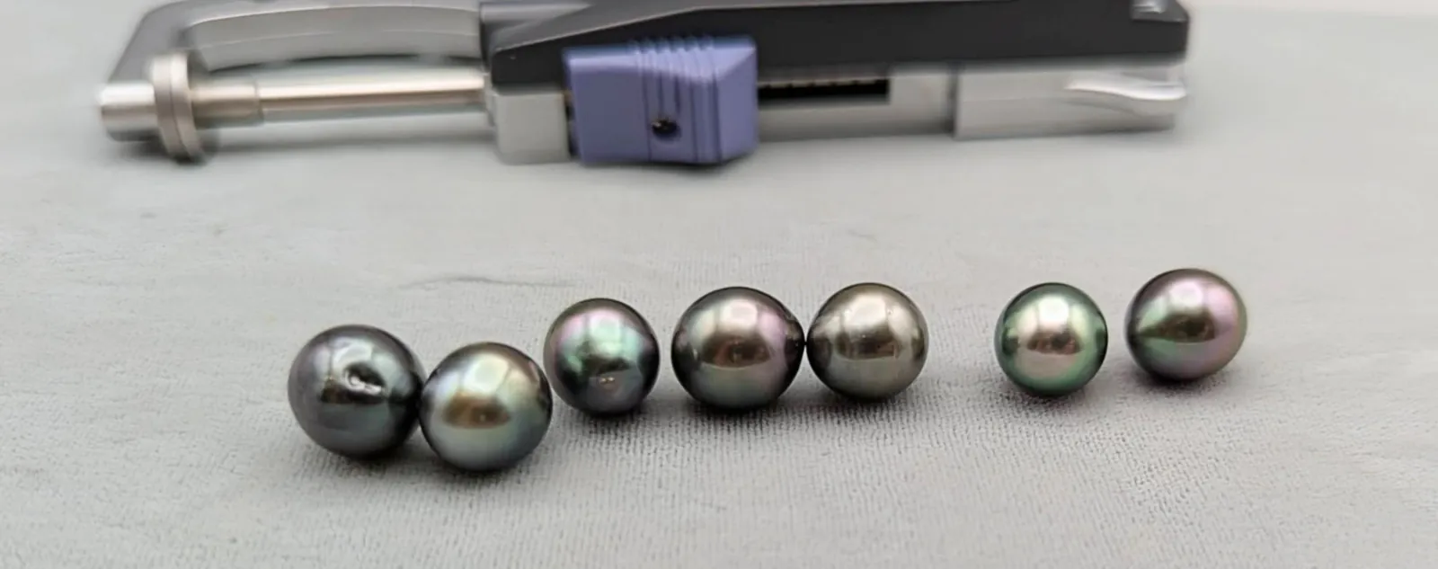 Tahitian pearls with varied overtones beside a digital caliper